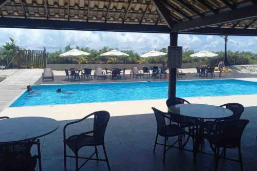 a pool with tables and chairs and people in a swimming pool at Condomí. Praia da Pérola -Beira Mar-Ilhéus/Itacaré in Ilhéus