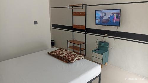 a bedroom with a bed and a tv on a wall at ARIRANG27 HOMESTAY in Siborongborong