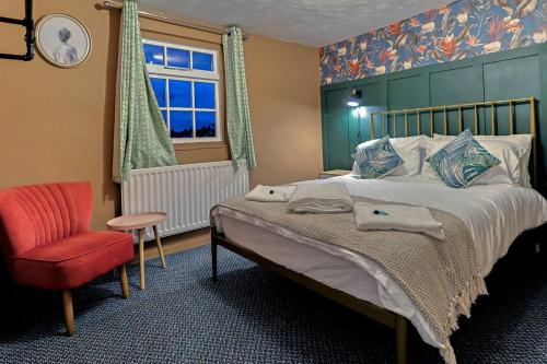 una camera con un letto e una sedia e una finestra di Beautiful 3-Bed Cottage in Burnham-on-Crouch a Burnham-on-Crouch