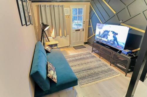un soggiorno con divano blu e TV di Beautiful 3-Bed Cottage in Burnham-on-Crouch a Burnham-on-Crouch