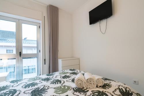 a bedroom with a bed with towels and a flat screen tv at Moreira 284 in Porto