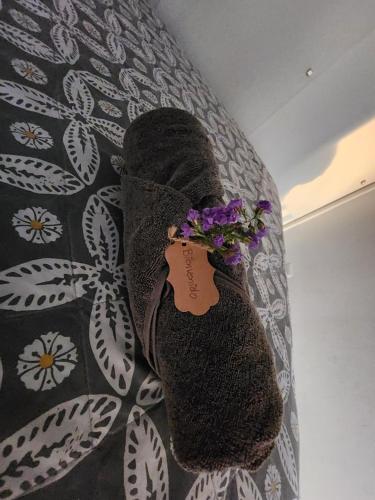 a pair of shoes with purple flowers on a bed at Apartamento Granat, con parqueo en Cuatro grados norte in Guatemala