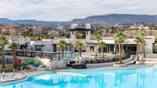 a large pool with palm trees and buildings at Rock Creek at Desert Color townhouse in St. George