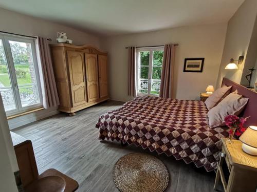 ein Schlafzimmer mit einem Bett und zwei Fenstern in der Unterkunft Manoir du Taillis in Heugon