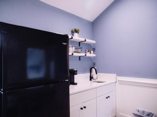 a kitchen with a black refrigerator and white cabinets at Wild Horse Inn in Corolla