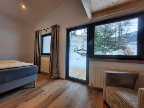 a bedroom with two windows and a bed and a chair at Ferienhaus Anna in Sölden