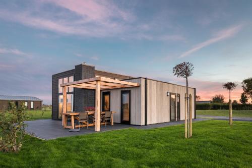 a small house with a table in a field at Summio Vakantiepark Zeedijk in Herkingen