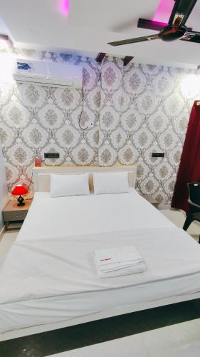 a white bed in a room with a wall at Hotel Dwarika in Chandrapur