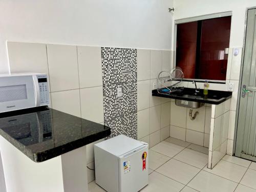 a small kitchen with a microwave and a sink at Casa da Vó Maria! Studio 08 in Goiânia