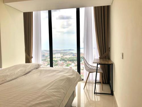 een slaapkamer met een bed en een stoel voor een raam bij Sea View One Bedroom Apartment In Bluhen Tower in Batam Center