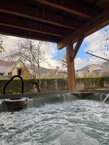 una bañera de hidromasaje en un patio trasero con agua en Casa Neste: Grange rénovée haut de gamme, en Arreau