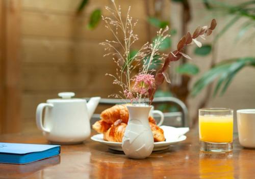 a table with a plate of pastries and a cup of orange juice at Hôtel La Nouvelle République & Hammam in Paris