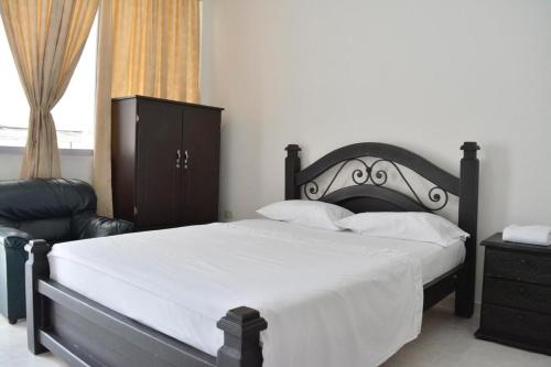 a bedroom with a large bed and a chair at Hotel La Mansión del Sol in Tuluá