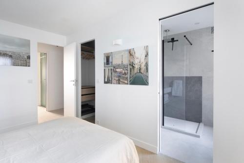 ein Schlafzimmer mit einem weißen Bett und einer Glaswand in der Unterkunft Loft 52m²+parking à 15 min de Paris centre in Les Lilas