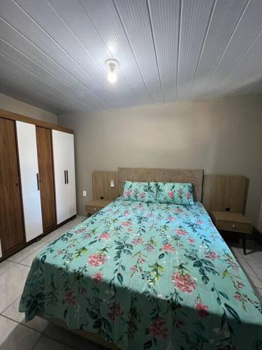 a bedroom with a large bed with a floral bedspread at Casa na Cachoeira Do Bom Jesus s in Florianópolis