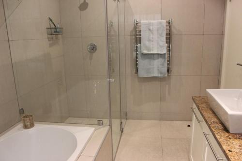 La salle de bains est pourvue d'une douche, d'une baignoire et d'un lavabo. dans l'établissement Leopard Tree Cottage, à Franschhoek