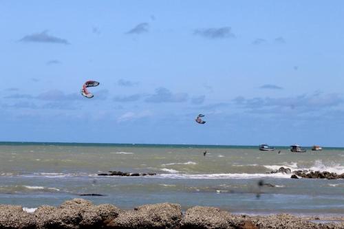 a group of people flying kites over the ocean at Amigos do Vento Pousada e Kite Point in Touros