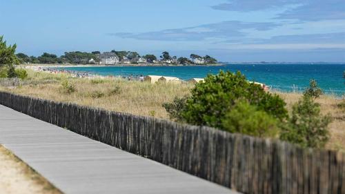 a wooden fence next to a beach with a boardwalk at Camping le Dolmen, Carnac, Morbihan in Carnac