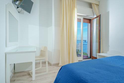 Schlafzimmer mit einem Bett, einem Schreibtisch und einem Fenster in der Unterkunft Hotel Oriente in Vico Equense