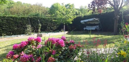 a garden with pink flowers and a bench in the background at La Meïzou, gîte - chambres d hôtes à Champeix in Champeix