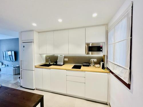 a kitchen with white cabinets and a white refrigerator at Apartamento, piscina y parking Granada Tico Medina in Granada