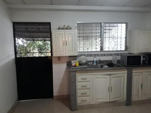 eine Küche mit weißen Schränken und einer schwarzen Tür in der Unterkunft La Casa de Eyi 