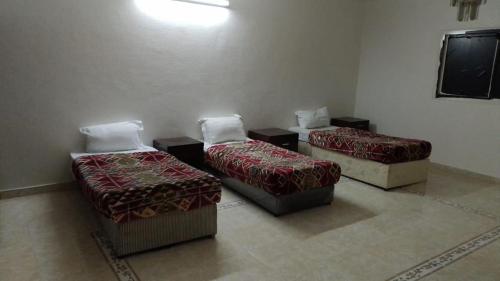 a room with three beds and a flat screen tv at فندق رحيق الذهبي in Al Madinah