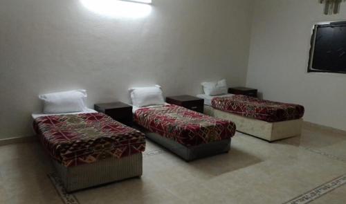 3 Betten in einem Zimmer mit einem TV in der Unterkunft فندق رحيق الذهبي in Medina