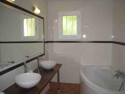 uma casa de banho com 2 lavatórios, uma banheira e um espelho. em JARDIN DE CAMILLE LLAURO em Llauro