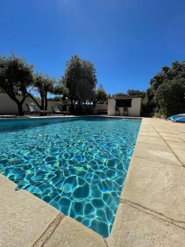 une piscine avec de l'eau bleue devant une maison dans l'établissement Belle Maison en Provence, à Sérignan-du-Comtat
