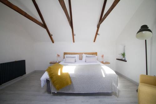 a bedroom with a white bed with a yellow blanket on it at Barnwell Cottage *Stunning Cornish Cottage* Oozing Charm + Comfort in Cubert