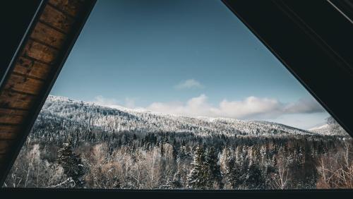 a view of a snow covered mountain from a window at Na Jeżynowej Polanie z gorącą balia in Wetlina