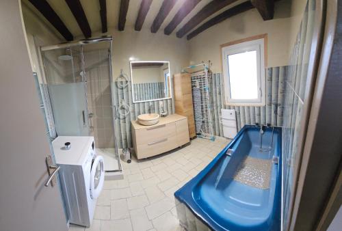 La salle de bains est pourvue d'une douche et d'une baignoire bleue. dans l'établissement Gîte des Bois Rimbert, à Beuzeville