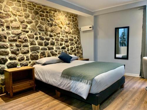 a bedroom with a stone wall and a bed at Casa Encuentro San Blas in Cusco