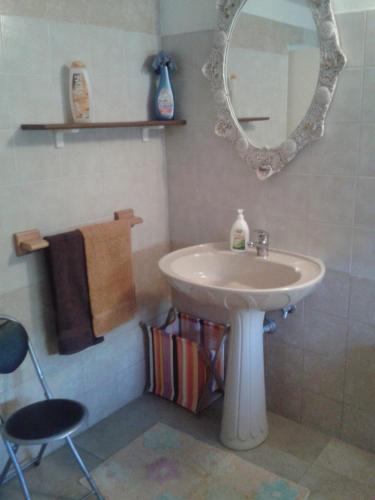 La salle de bains est pourvue d'un lavabo, d'un miroir et d'une chaise. dans l'établissement Villetta In Campagna, à Parabita
