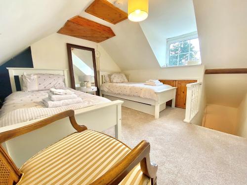 um quarto no sótão com 2 camas e um espelho em Bumblebee Cottage - Cosy Cottage in Area of Outstanding Natural Beauty em Hemel Hempstead