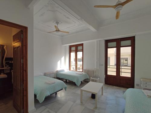 バレンシアにあるEntre la Estación y el Ayuntamientoのベッド2台と天井ファンが備わる客室です。