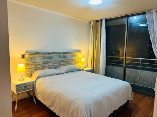 a bedroom with a white bed and a window at Departamento en Las Condes in Santiago