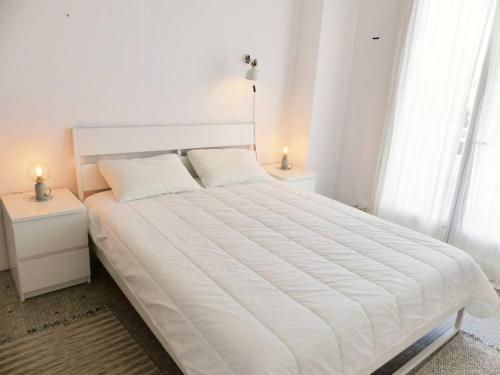 białe łóżko w białej sypialni z 2 lampami w obiekcie HOSSEGOR Plage Centrale Résidence ATLANTIC Appartement pour 4 personnes Wifi gratuit w mieście Soorts-Hossegor