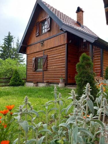 a log cabin with flowers in front of it at Brvnare Na Brdu in Šljivovica