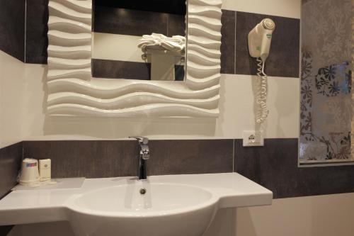 a bathroom with a white sink and a phone at Hotel Liberty in Levico Terme