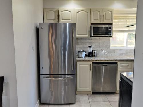 a stainless steel refrigerator in a kitchen with white cabinets at Spacious MBR Near Kennedy Subway & GO in Toronto