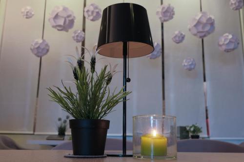 a candle and a lamp on a table with a potted plant at Hotel Liberty in Levico Terme