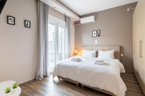 um quarto com uma cama branca e uma grande janela em More Athens Apartments em Atenas