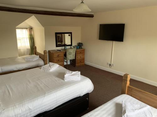 a hotel room with two beds and a television at The Cromwell Arms Inn in Bovey Tracey