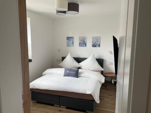 a bedroom with a bed with white sheets and blue pillows at Winkelschiffchen III mit Sauna in Juist