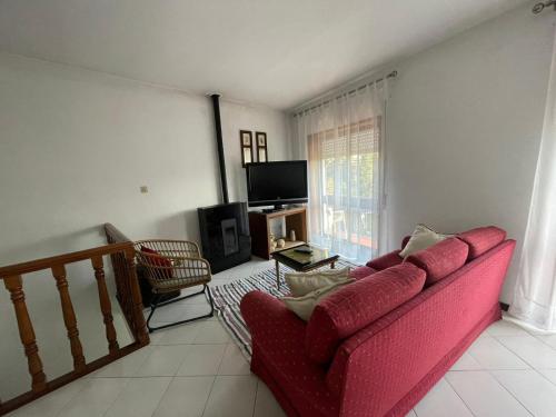 a living room with a red couch and a television at Casa Sr do Calvário in Paços de Ferreira
