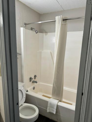 La salle de bains est pourvue d'une baignoire, de toilettes et d'une douche. dans l'établissement Heritage Inn, à Milledgeville