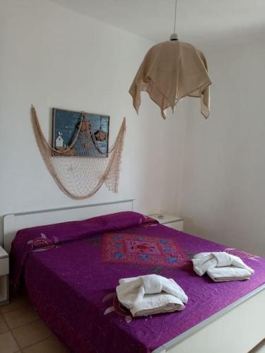 Un dormitorio con una cama morada con toallas. en Splendido appartamento a Lampedusa, con terrazzo ! en Lampedusa