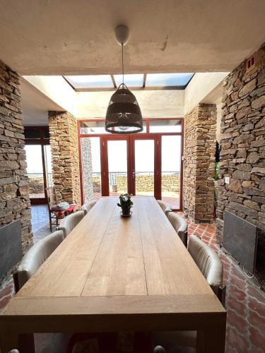 Cette chambre dispose d'une grande table en bois et d'un mur en pierre. dans l'établissement maison gaou bénat vue à 180°, à Bormes-les-Mimosas